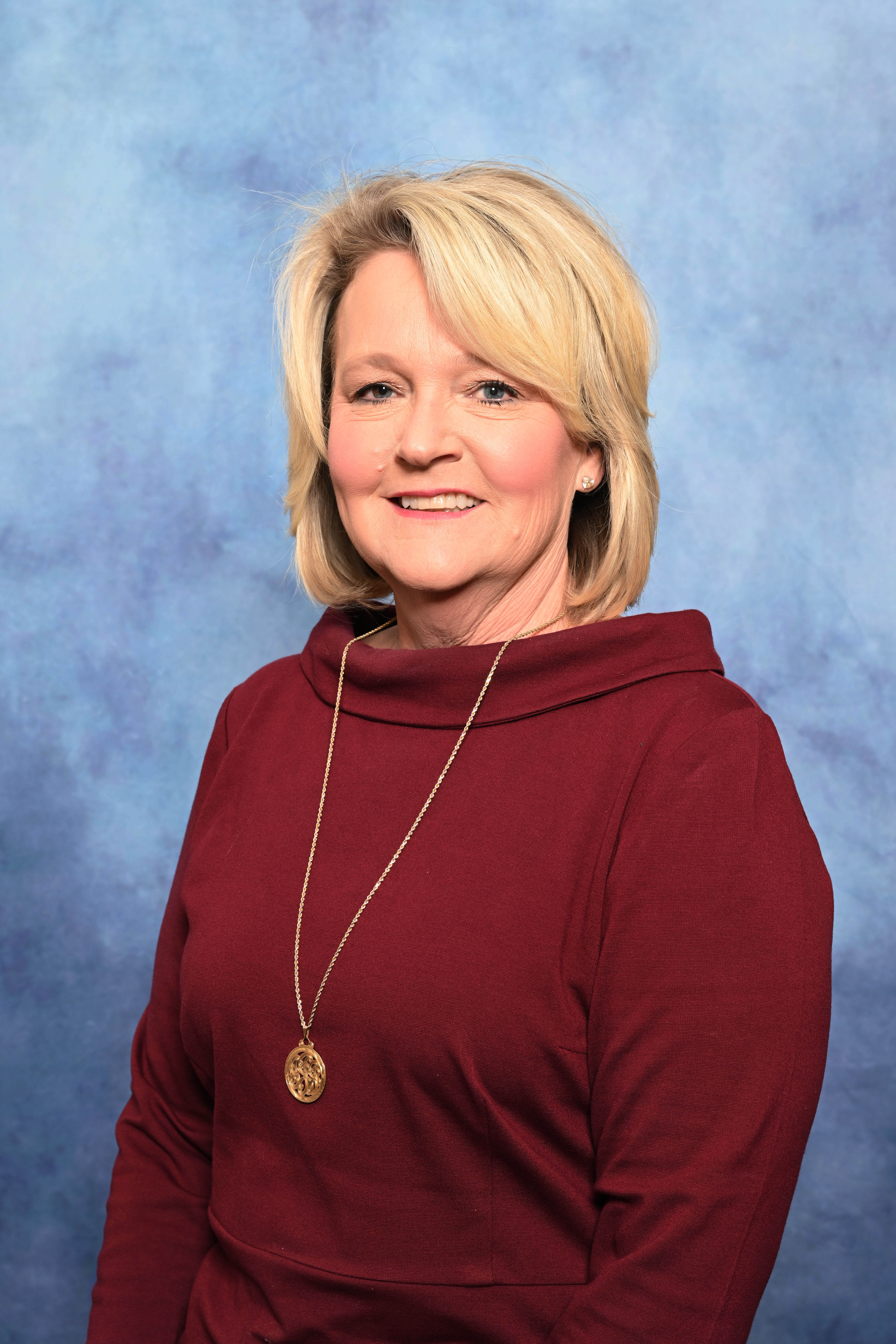 A woman in maroon with a gold necklace.