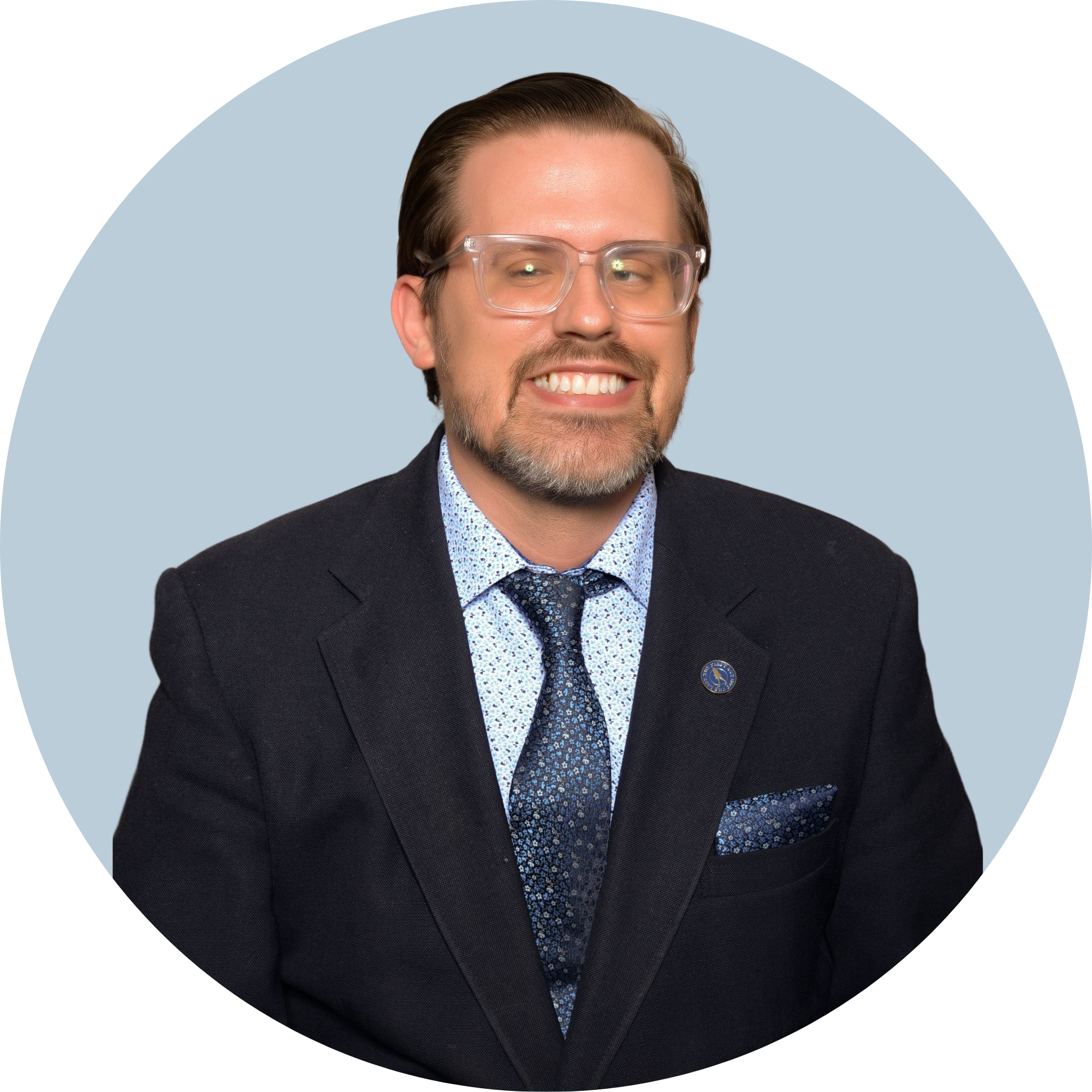 A man wearing glasses in a suit jacket and tie