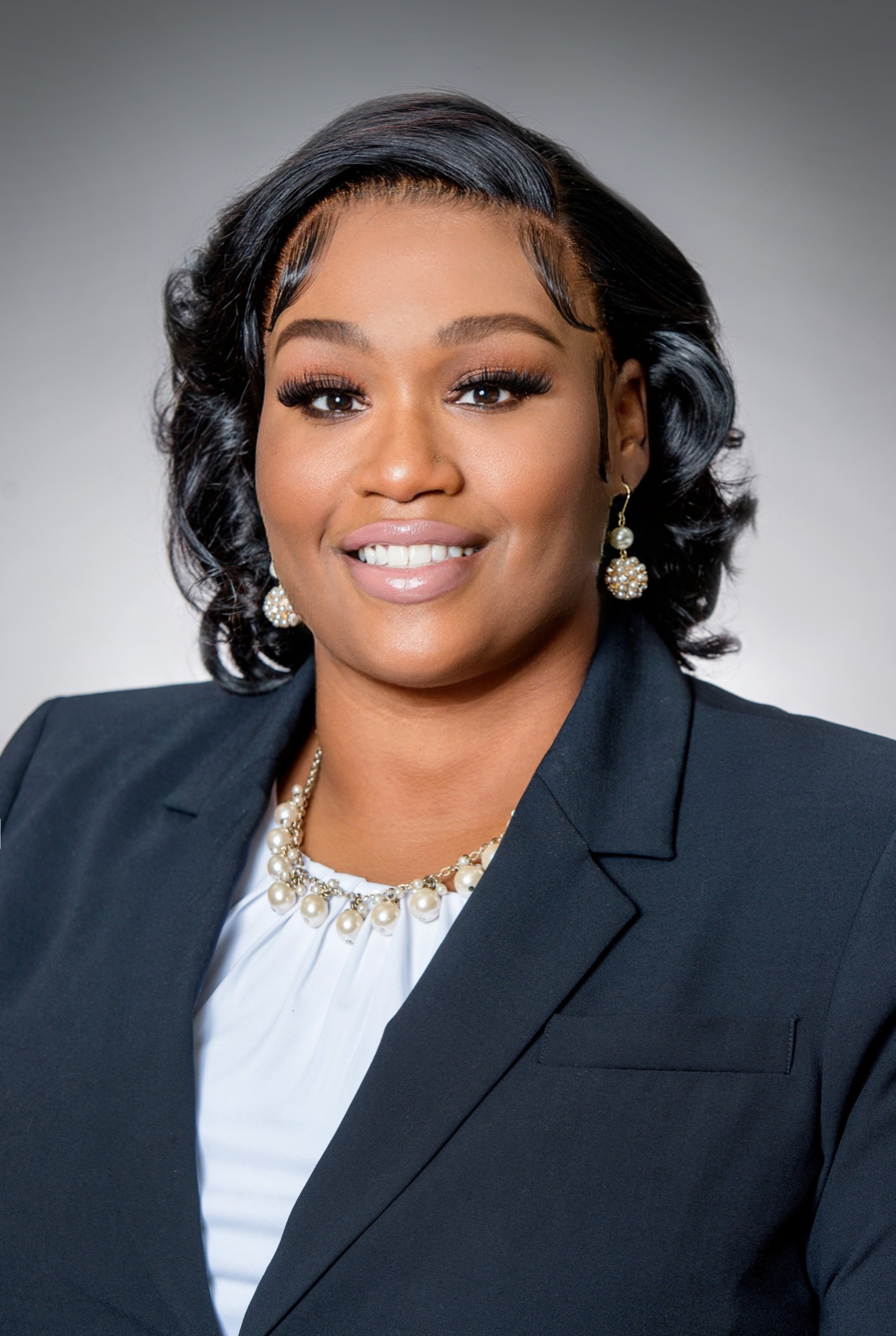 A smiling woman is wearing a suit jacket.