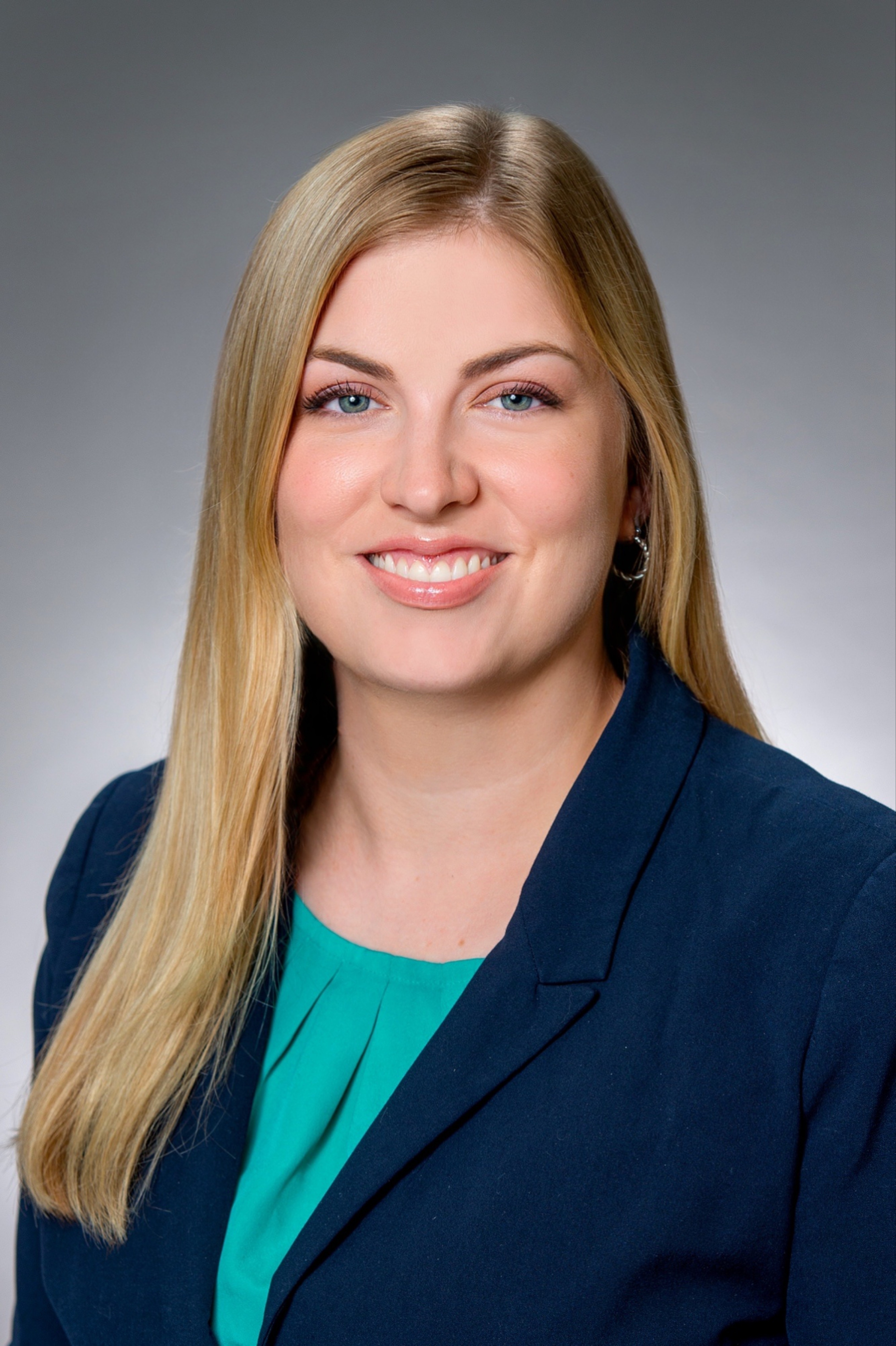 A woman in a dark jacket and a teal shirt.