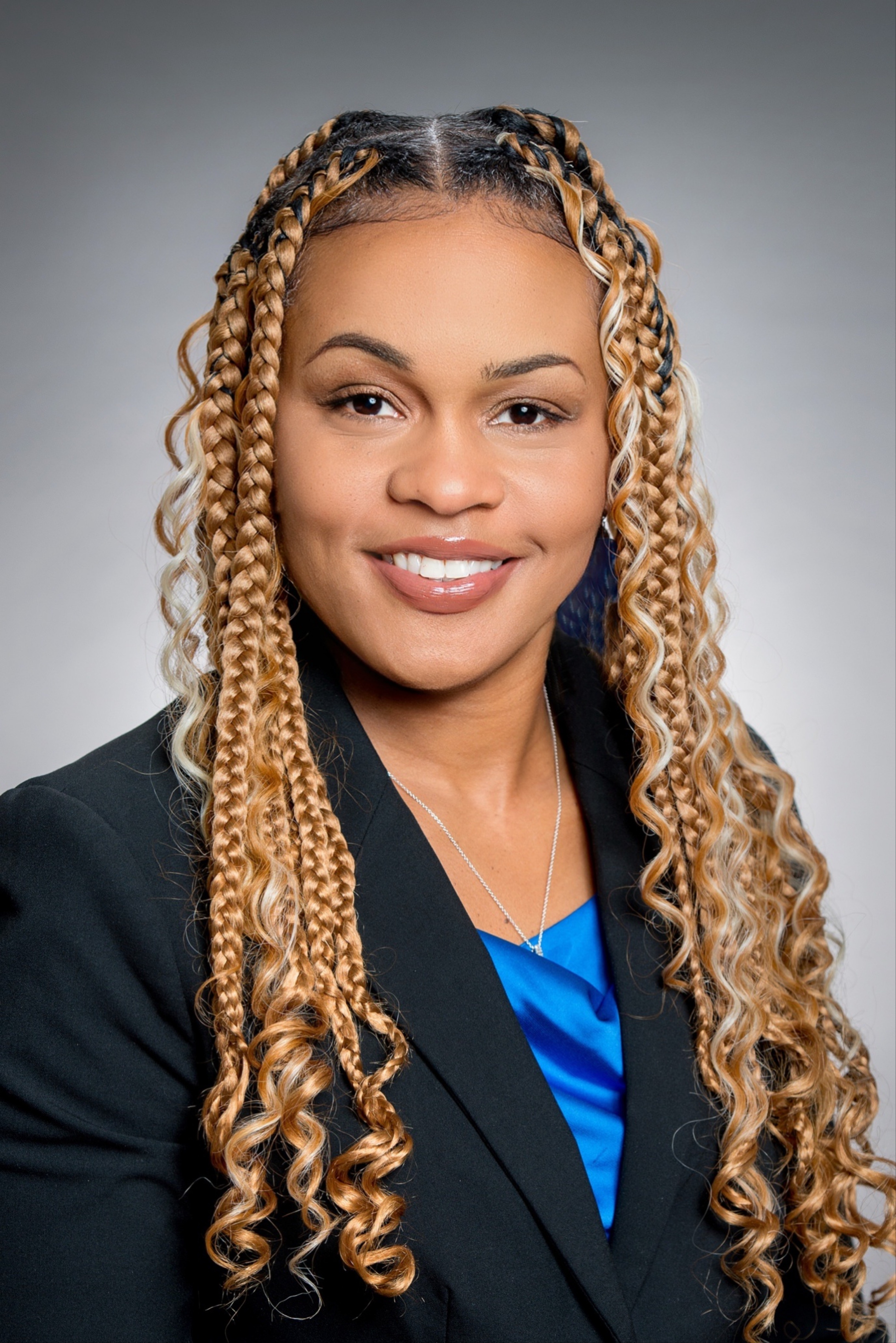 A woman in a cream sweater and black shirt is smiling.