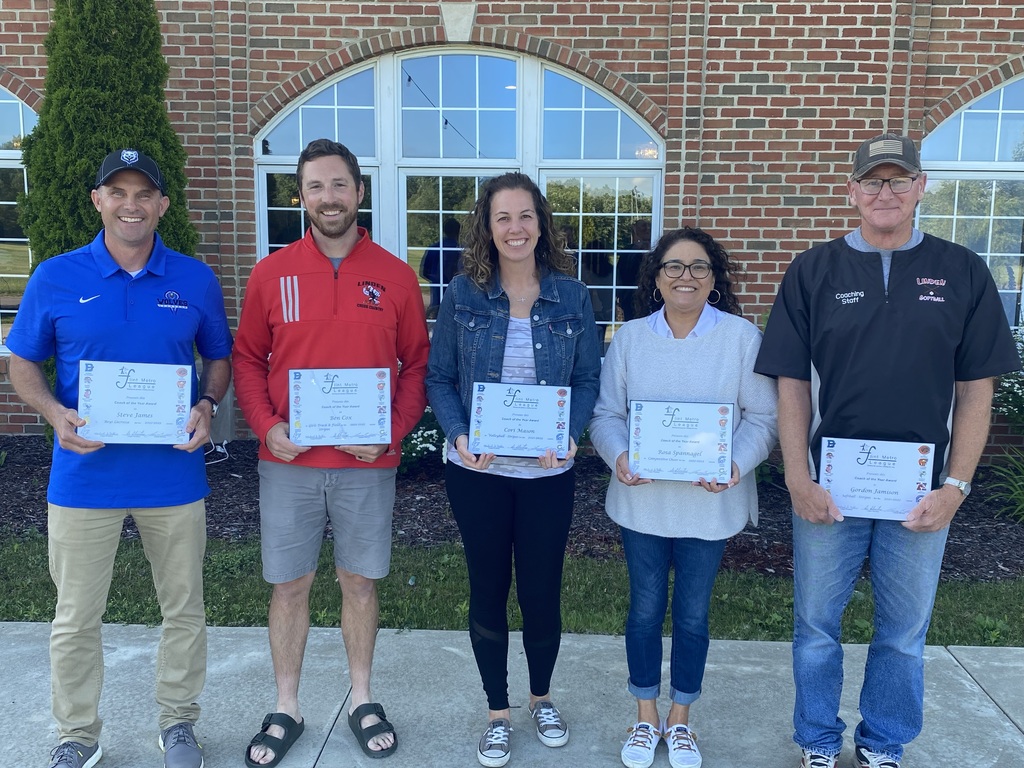 Coaches standing in a line holding certificates