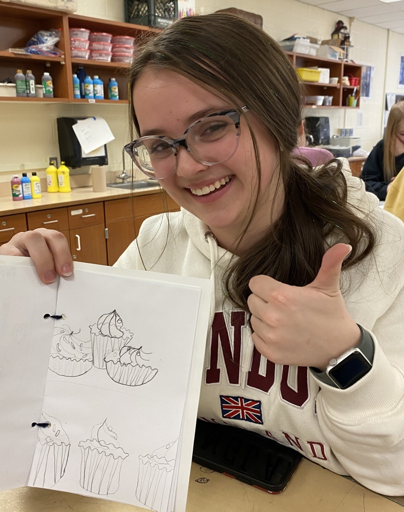 Girl showing a drawing of a cupcake with a thumbs up