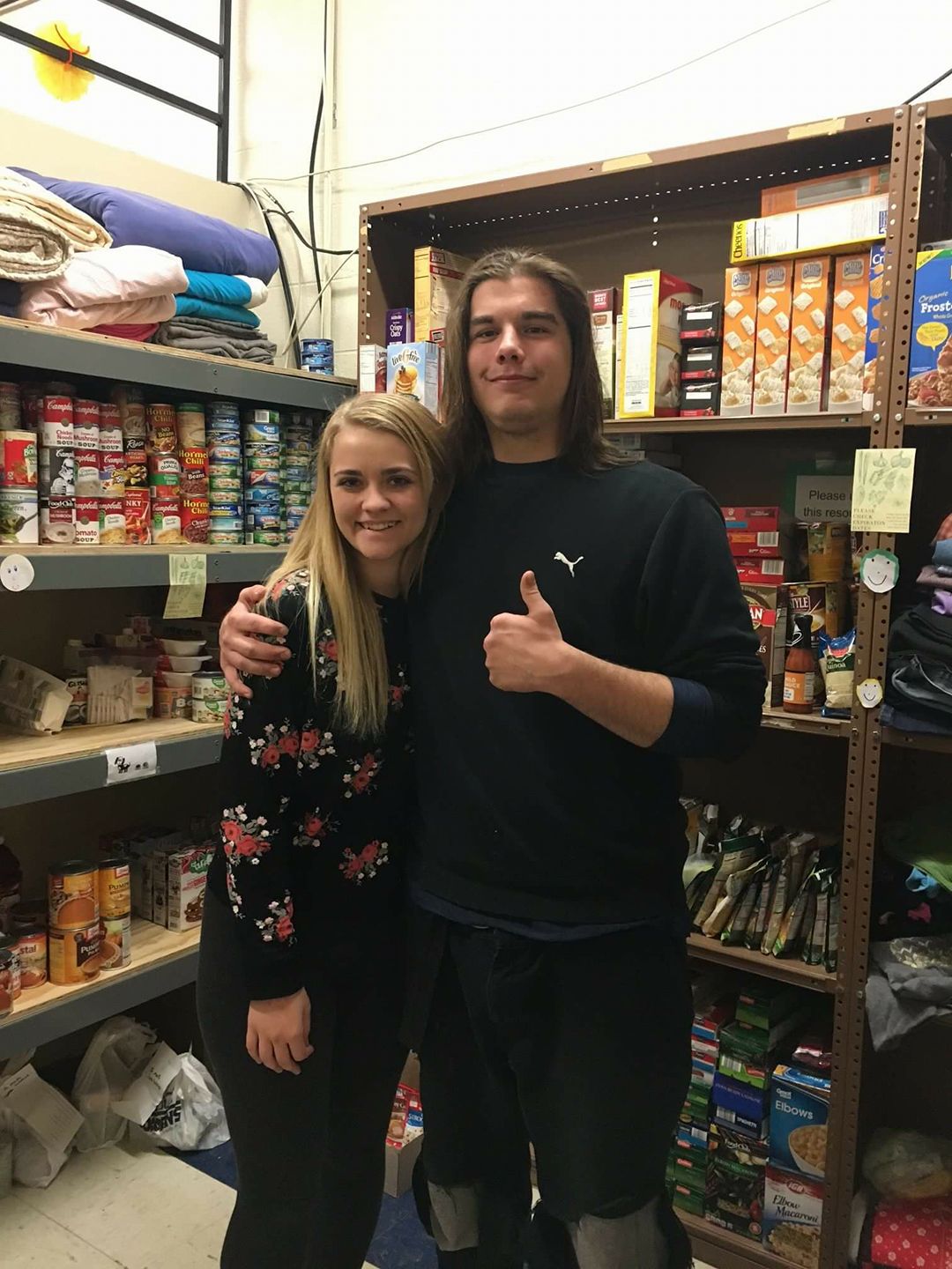 Two students standing in front of shelves with food 