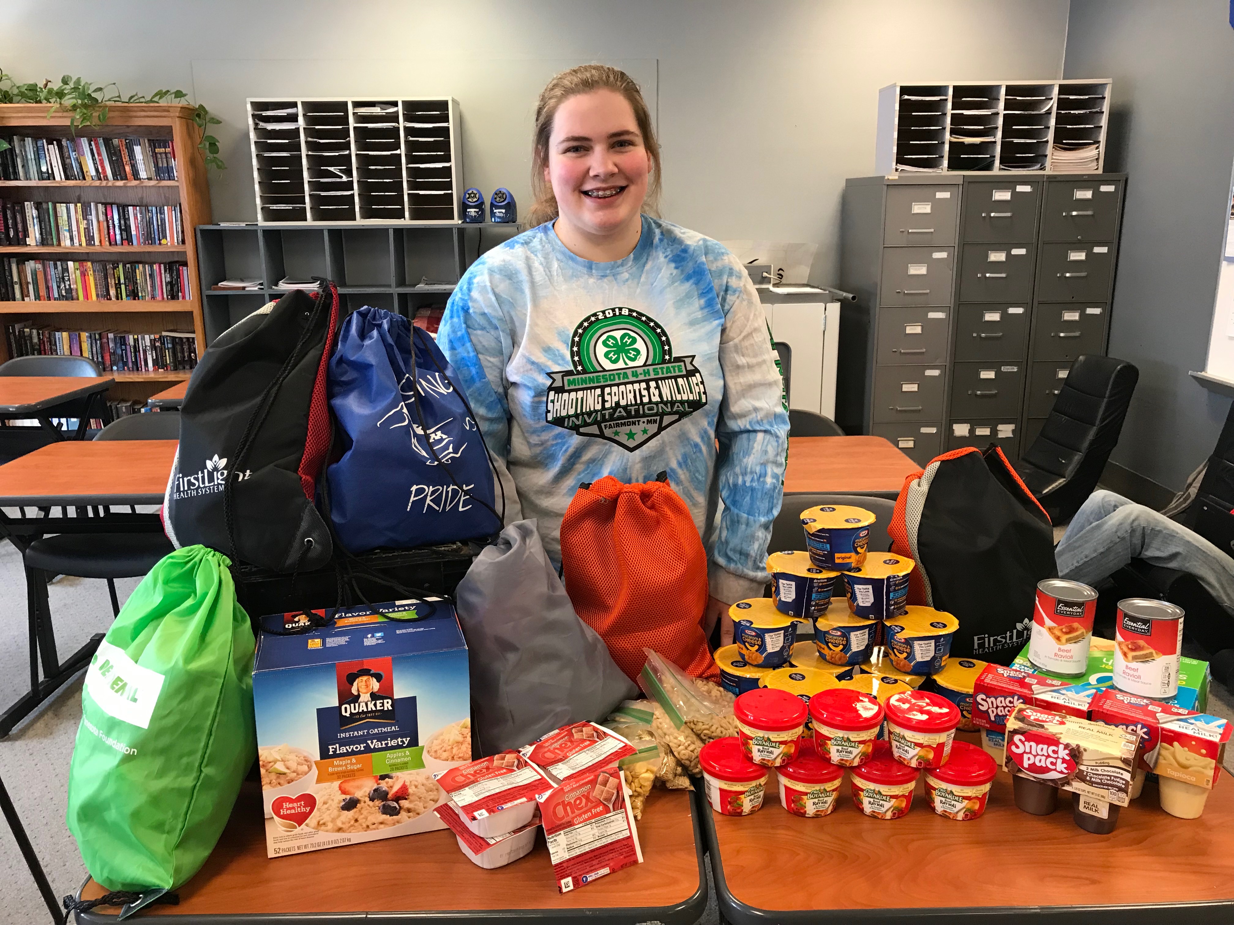 A student stand behind a table full of donations