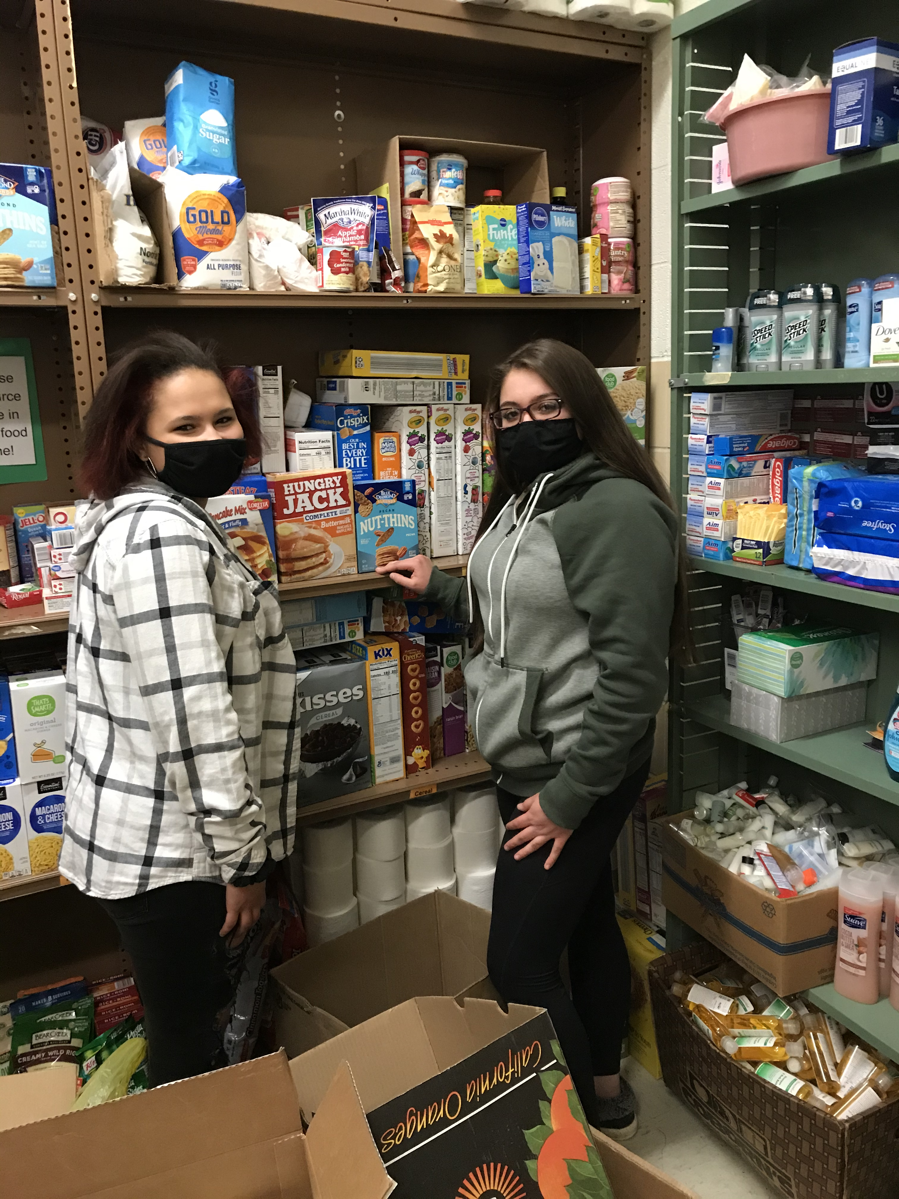 two students standing in front of shelves picking out some food