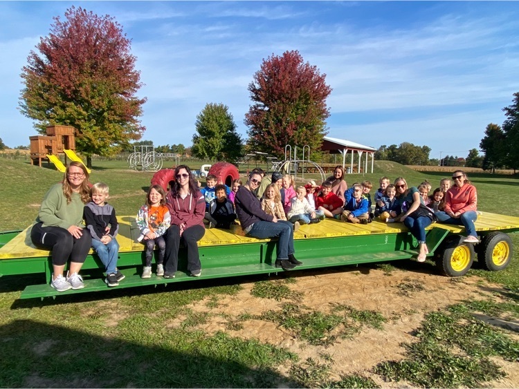 Parents and students sitting on a yellow and green trailer
