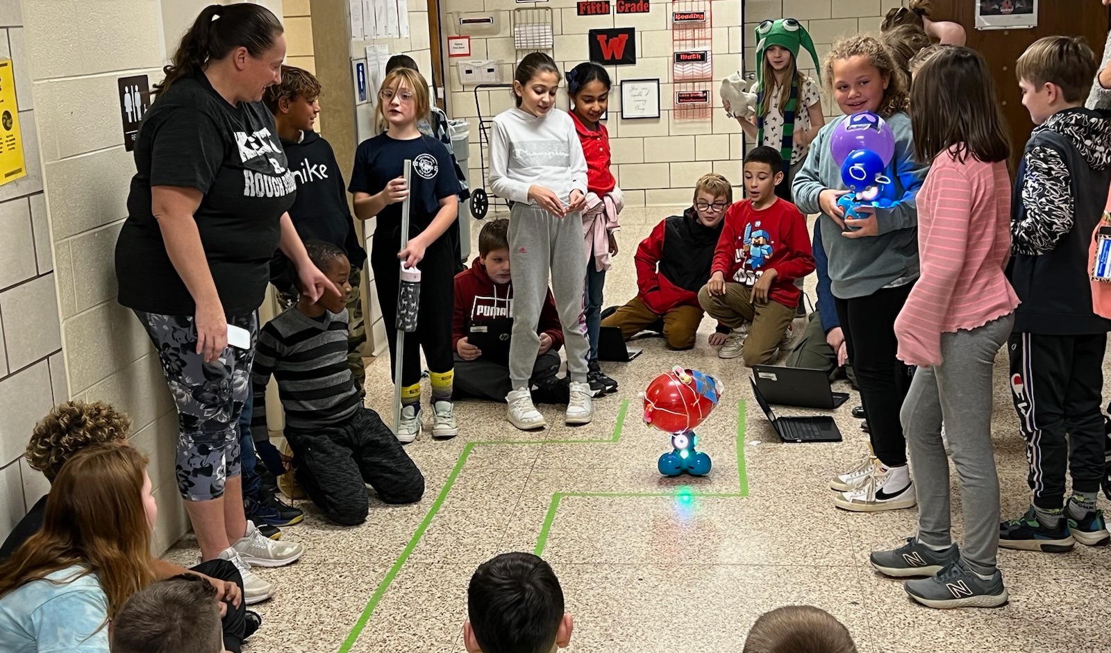 students in hallway looking at robot on floor