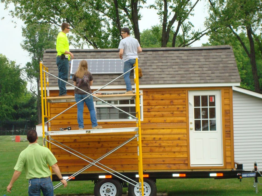 Construction students installing solar panels on a shed