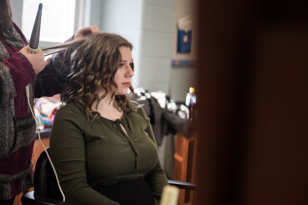 A student curling a woman's hair