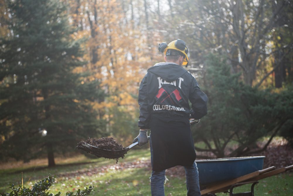 Student carrying a shovel full of dirt