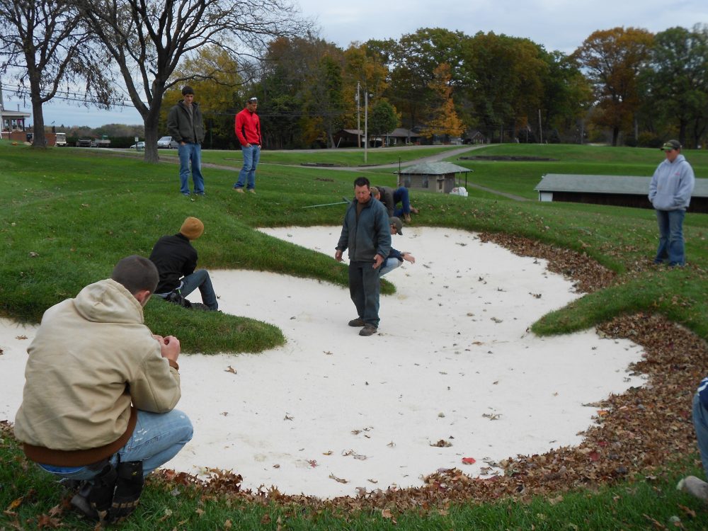 Students working in a golf course sand pit