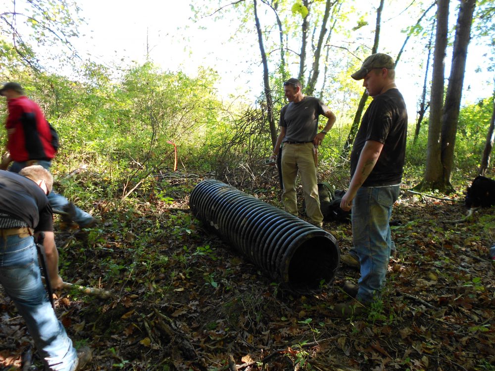 Students standing around a pipe