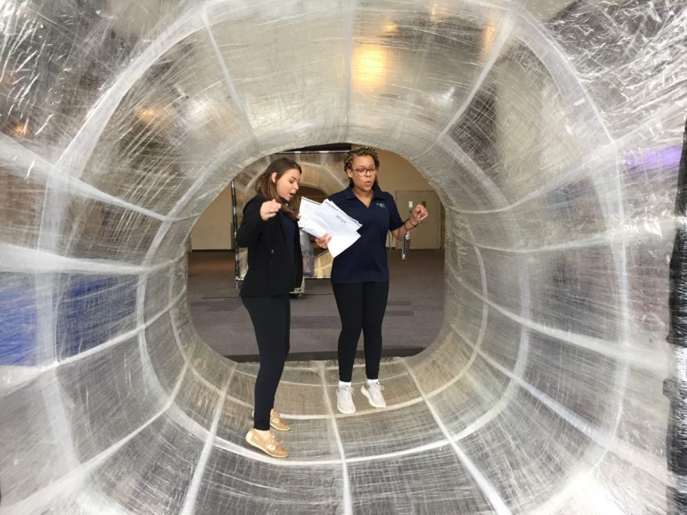 2 students walking through an inflatable tube
