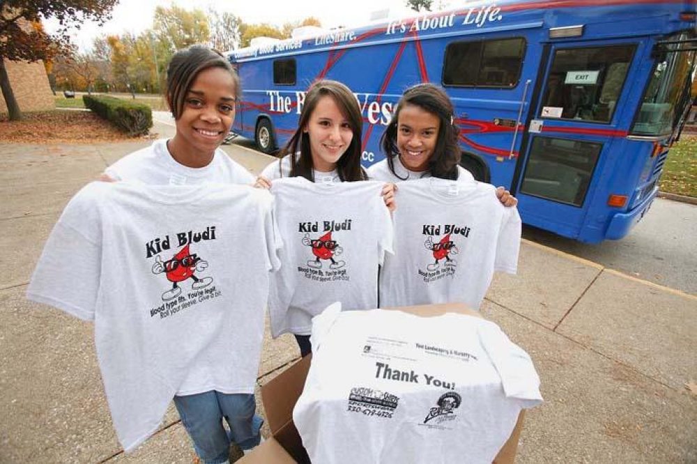 3 students holding up blood drive shirts