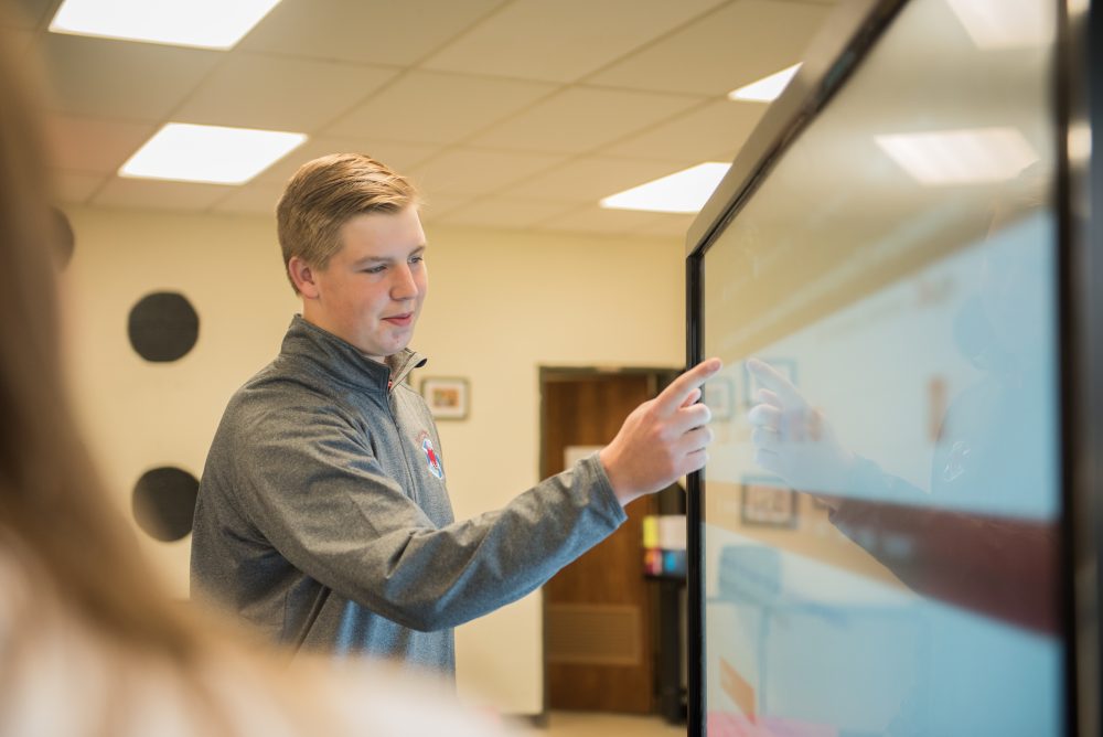 A student pointing to a smartboard