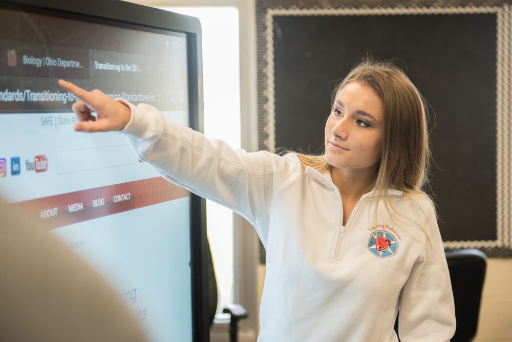 A student pointing to a smartboard