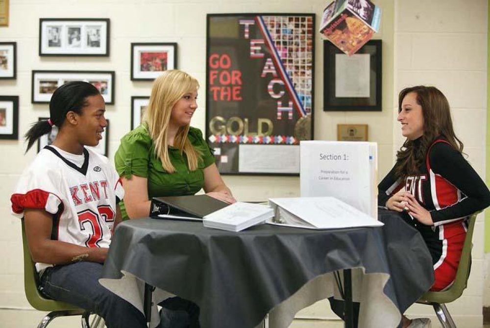3 students sitting around a table talking