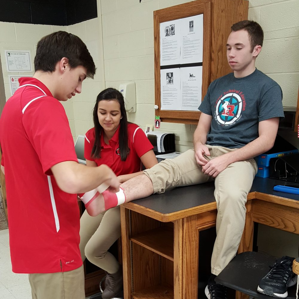 A student practing wrapping an ankle on another student