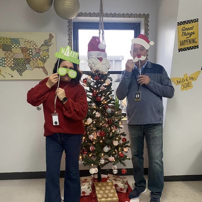 Staff members at Sloan-Hendrix posing with props in front of a Christmas Tree