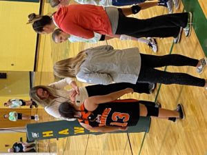 junior high volleyball players in huddles with coaches during game in gym. CPS players in black & orange uniforms