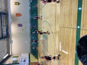 junior high volleyball players in huddles with coaches during game in gym. CPS players in black & orange uniforms