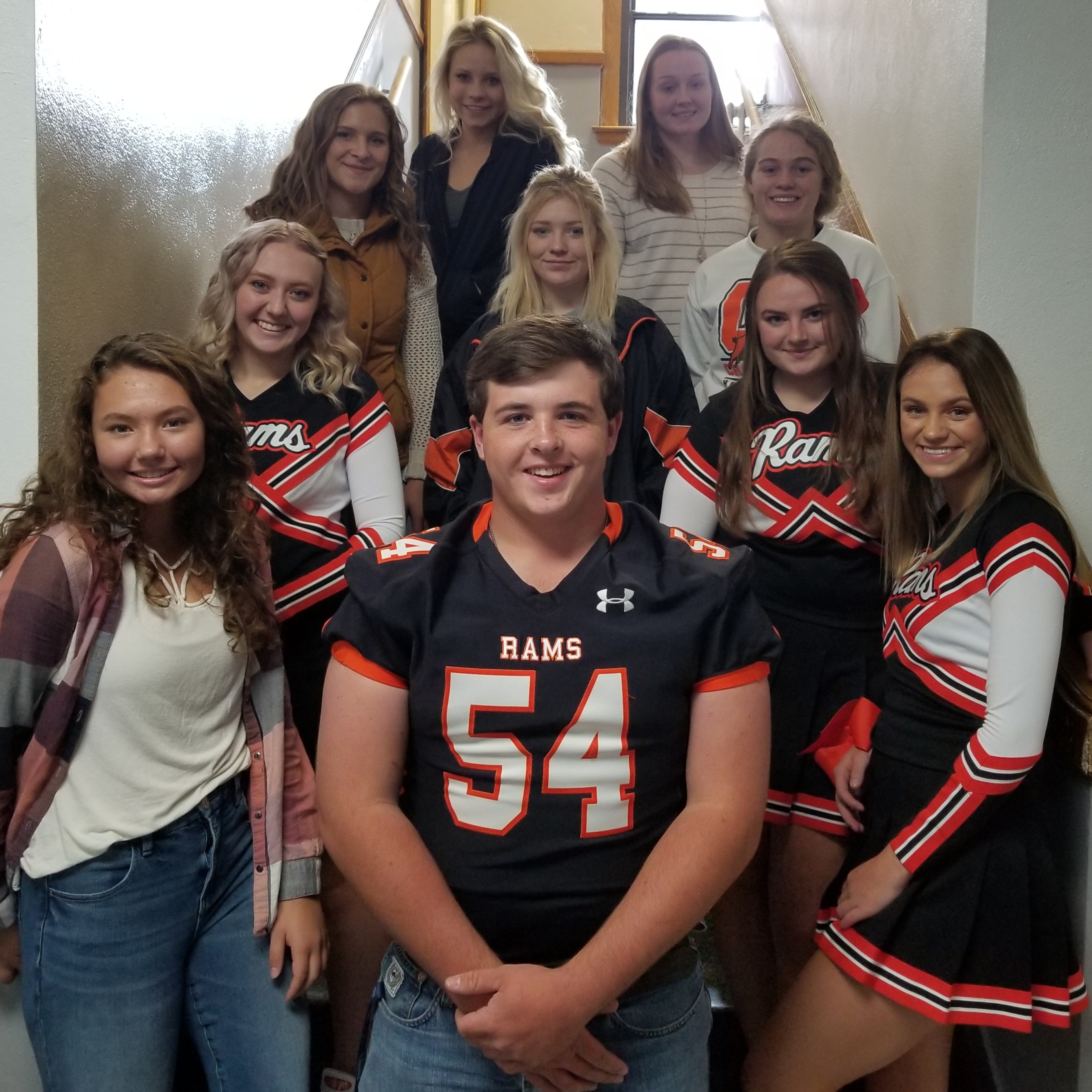 national honor society members photographed on stairwell. Many students are wearing jerseys from sports teams/activities
