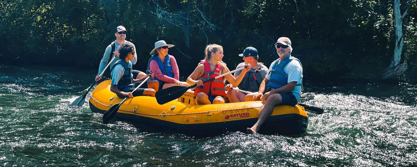 students and teacher in raft on river