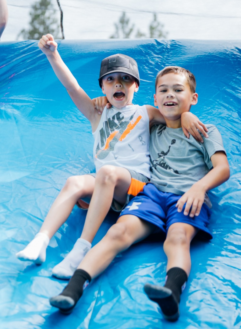 two boys laugh on an inflatable slide