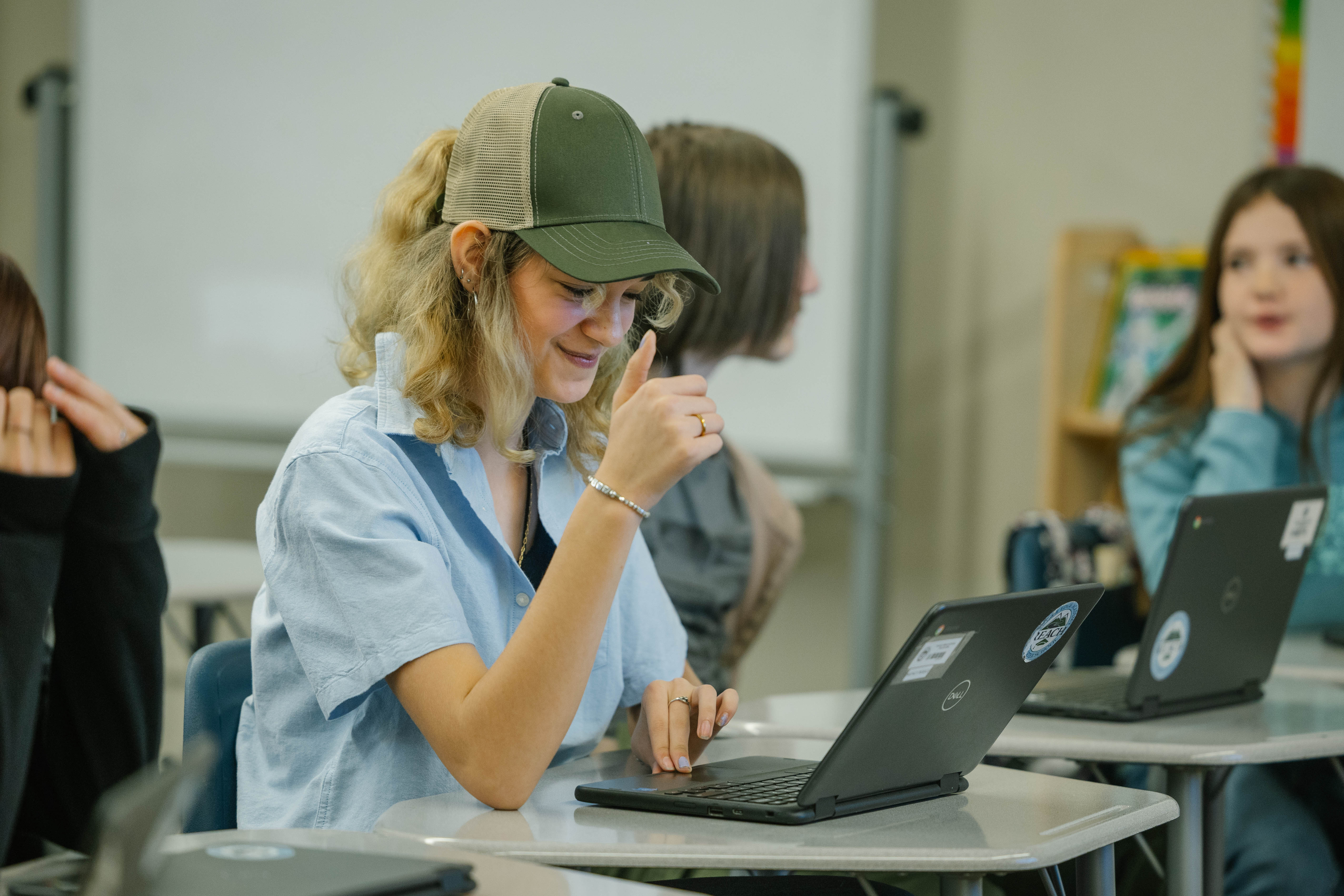 Student at desk with thumbs up