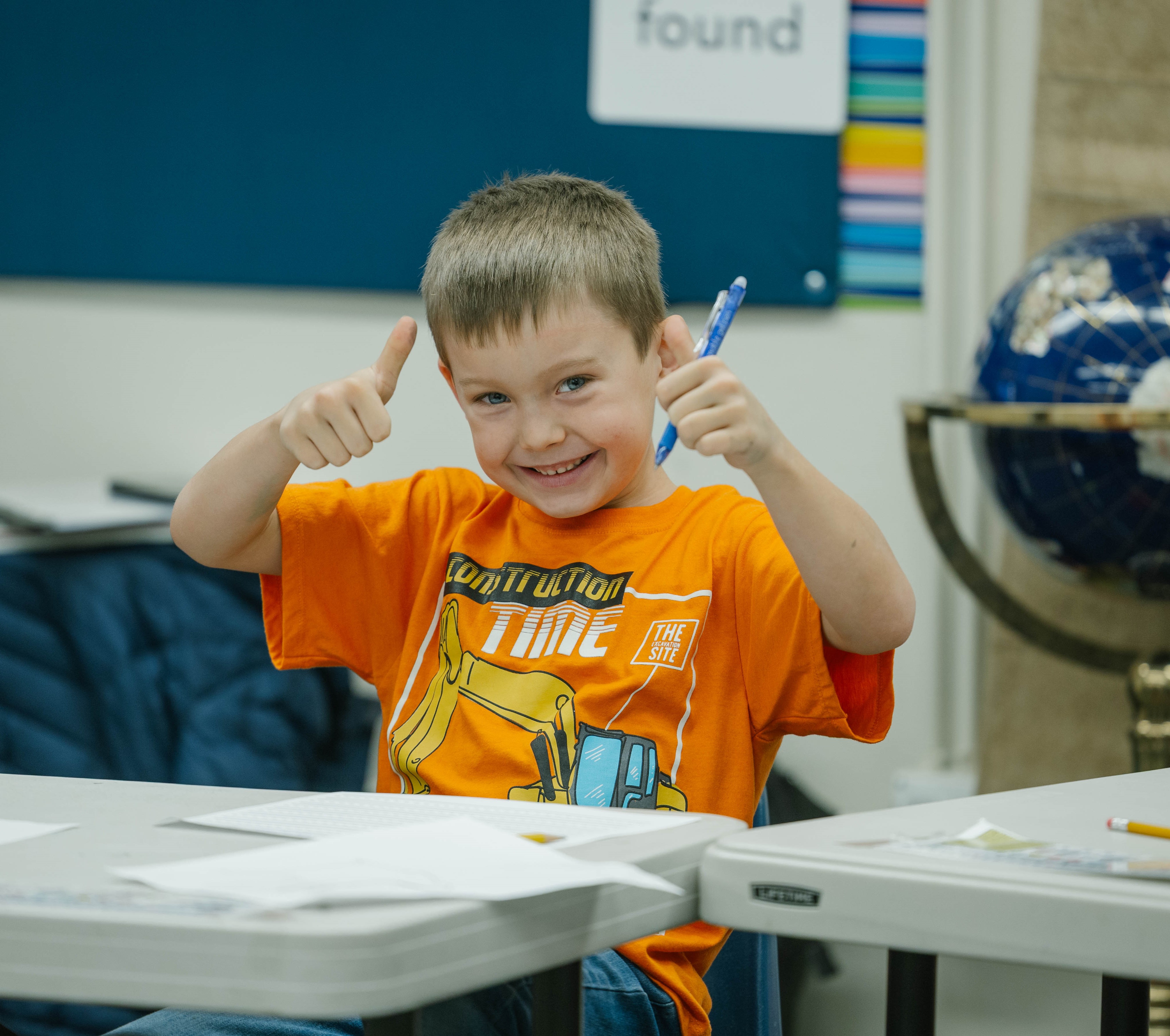 Student with thumbs up at desk