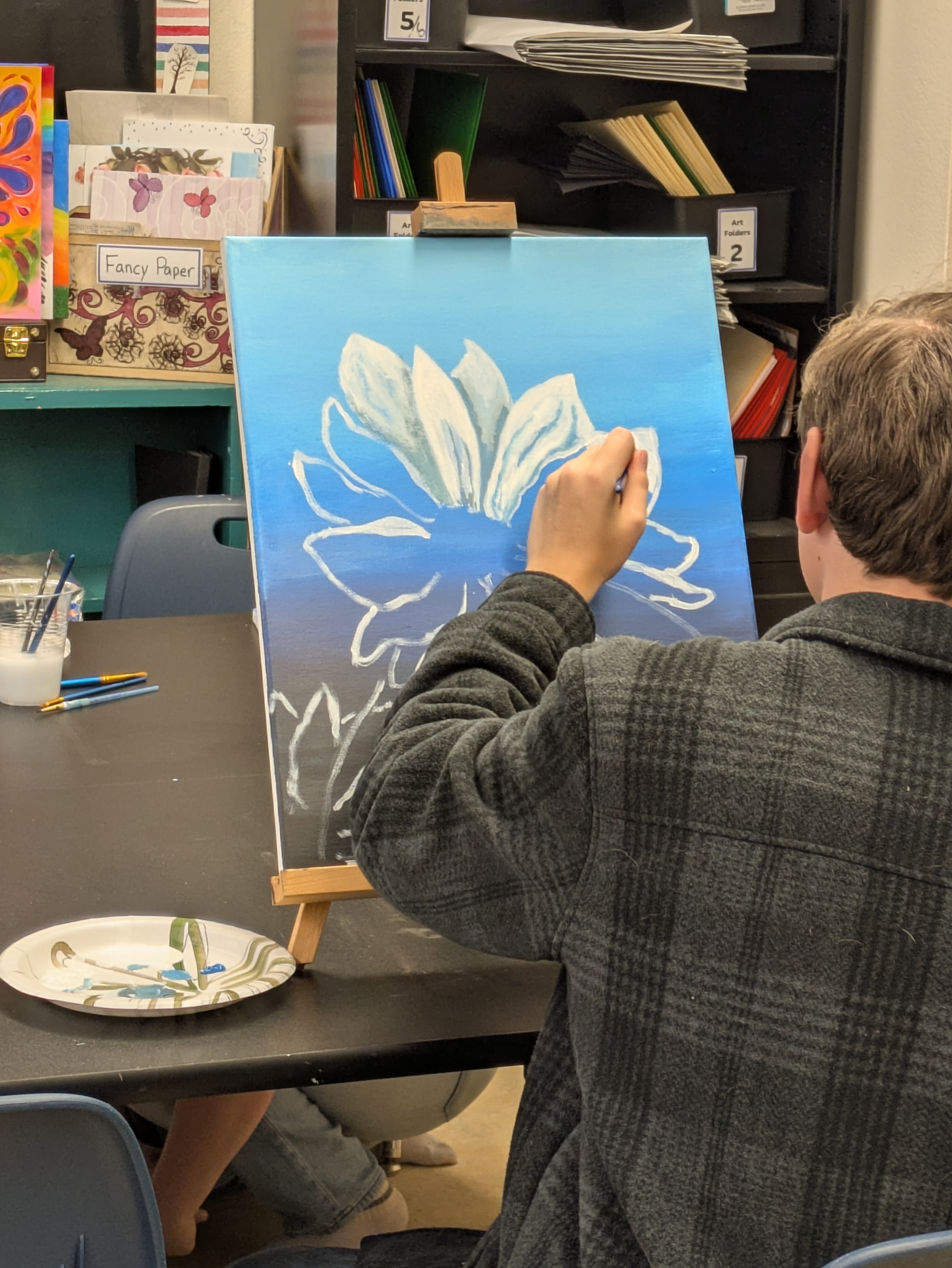 Student painting a flower on canvas