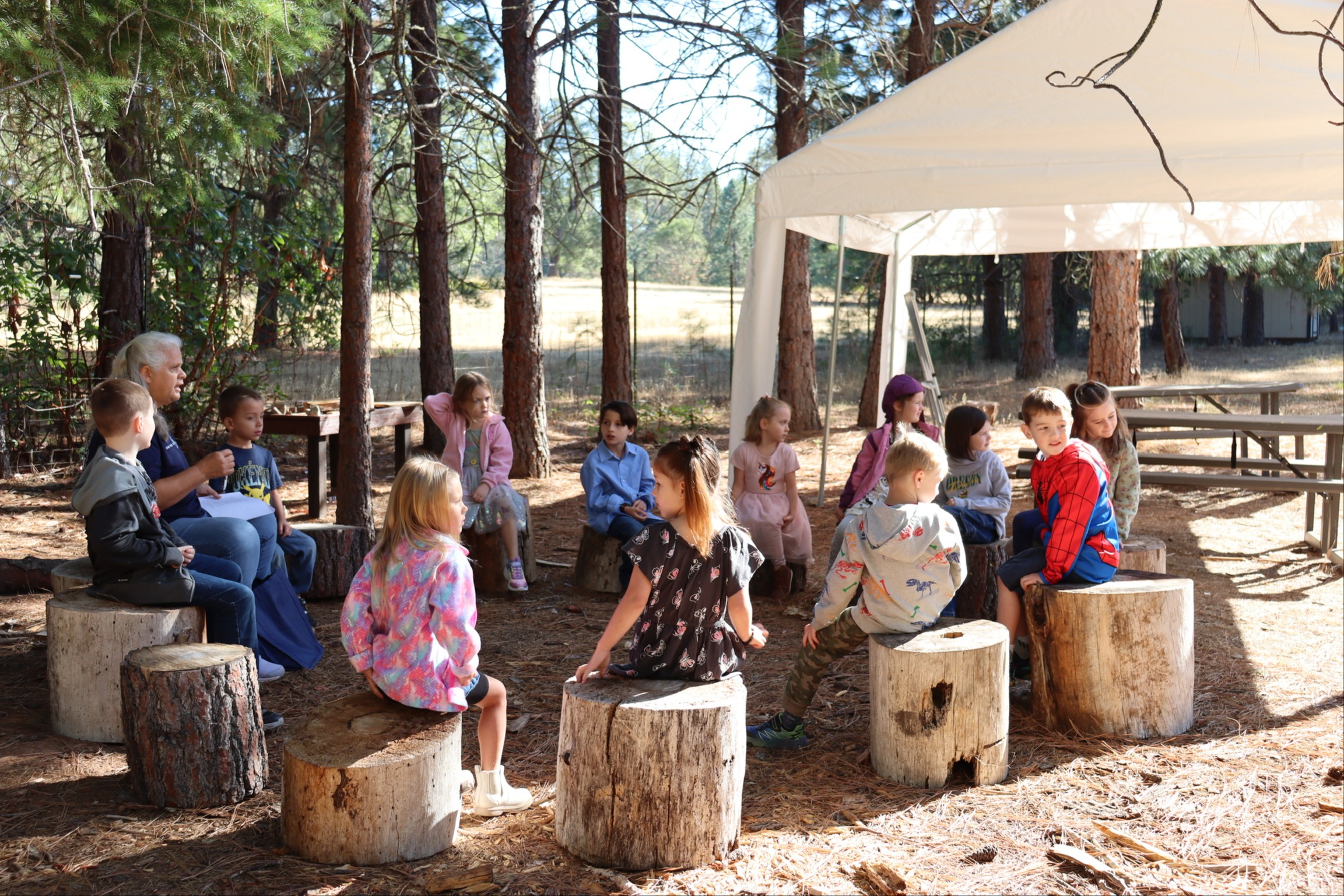 EV Campus students sitting outside on logs