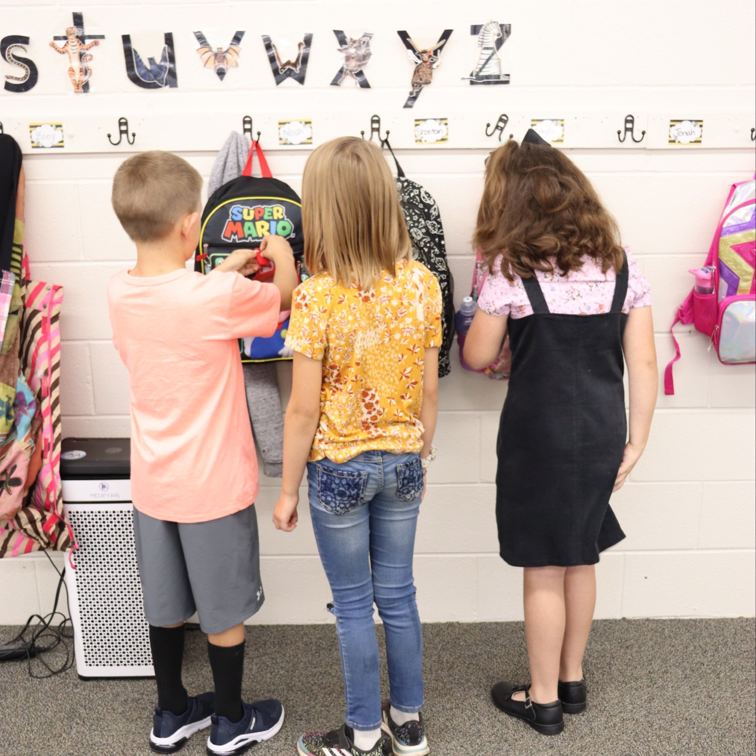EV Classroom student hanging backpacks on wall
