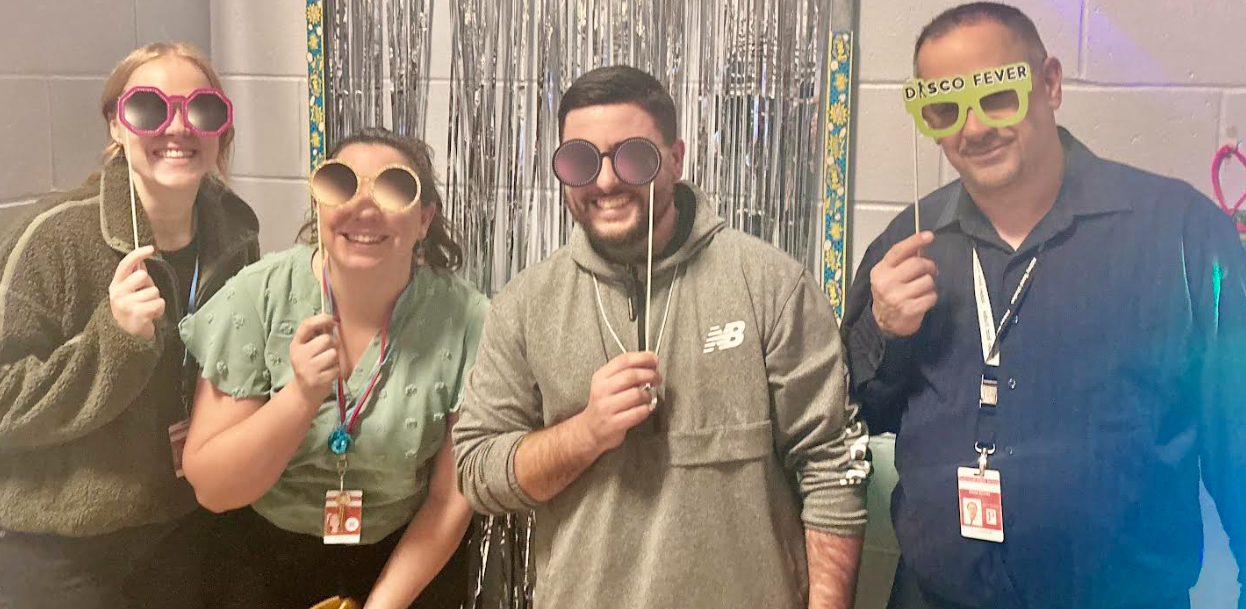 Ms. Paknis, Ms. Lathan, Mr. Soares, and Mr. Arruda pose in the photobooth at the UA Family Disco Night.