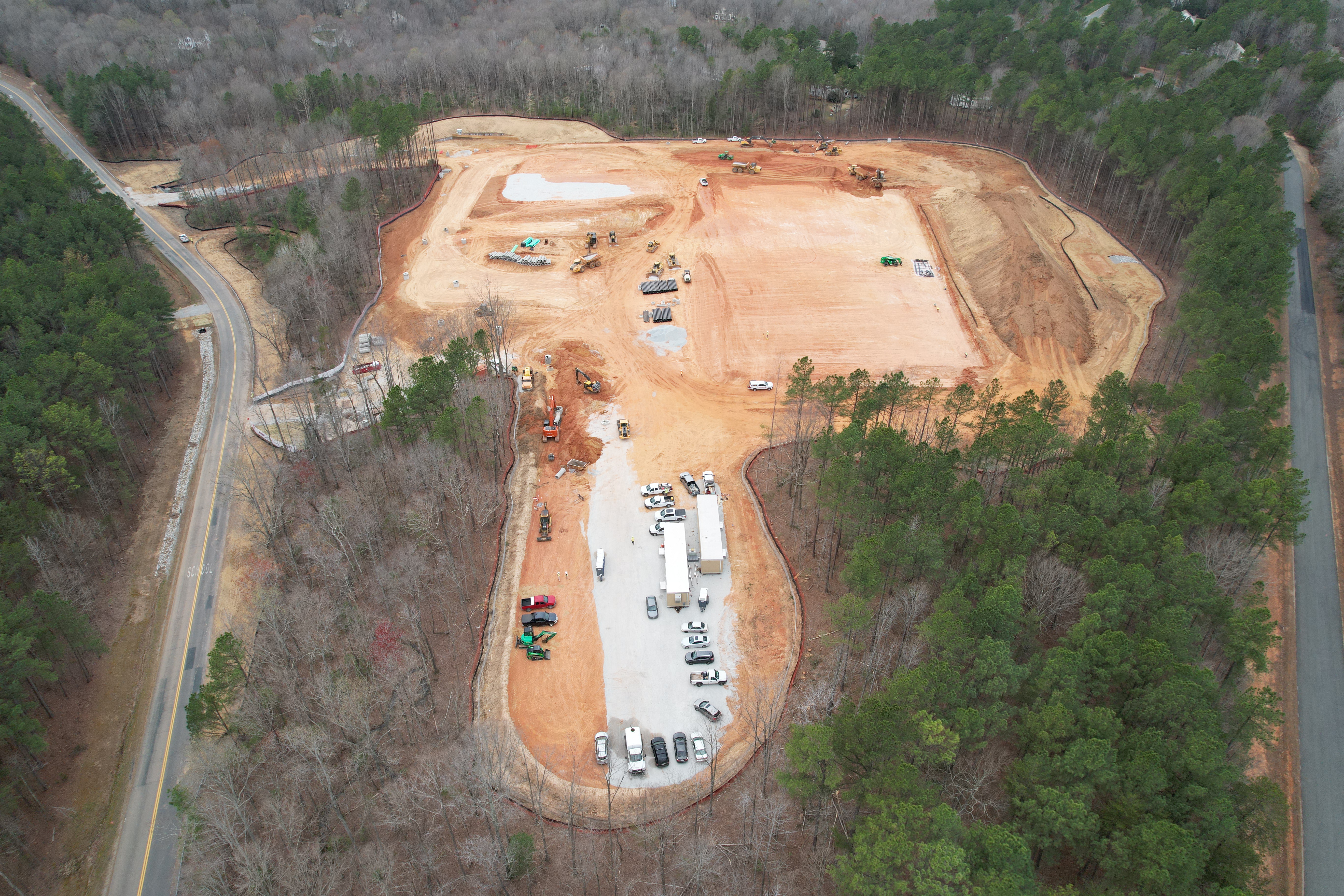 Drone image of site looking south showing bus loop with construction trailers and graded building pad