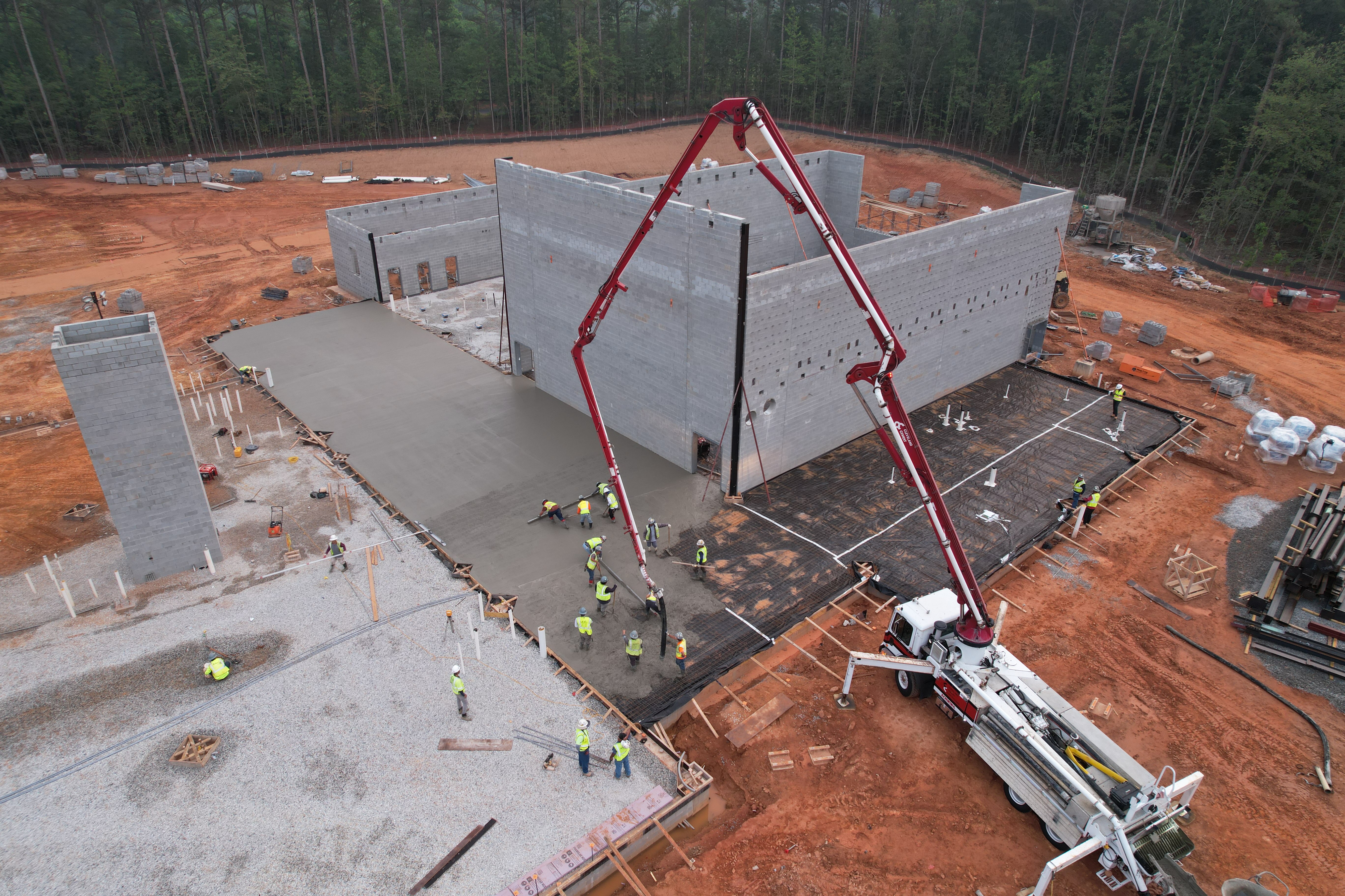 Large crane and crew lay concrete flooring in New GES cafeteria on 6/30/2023