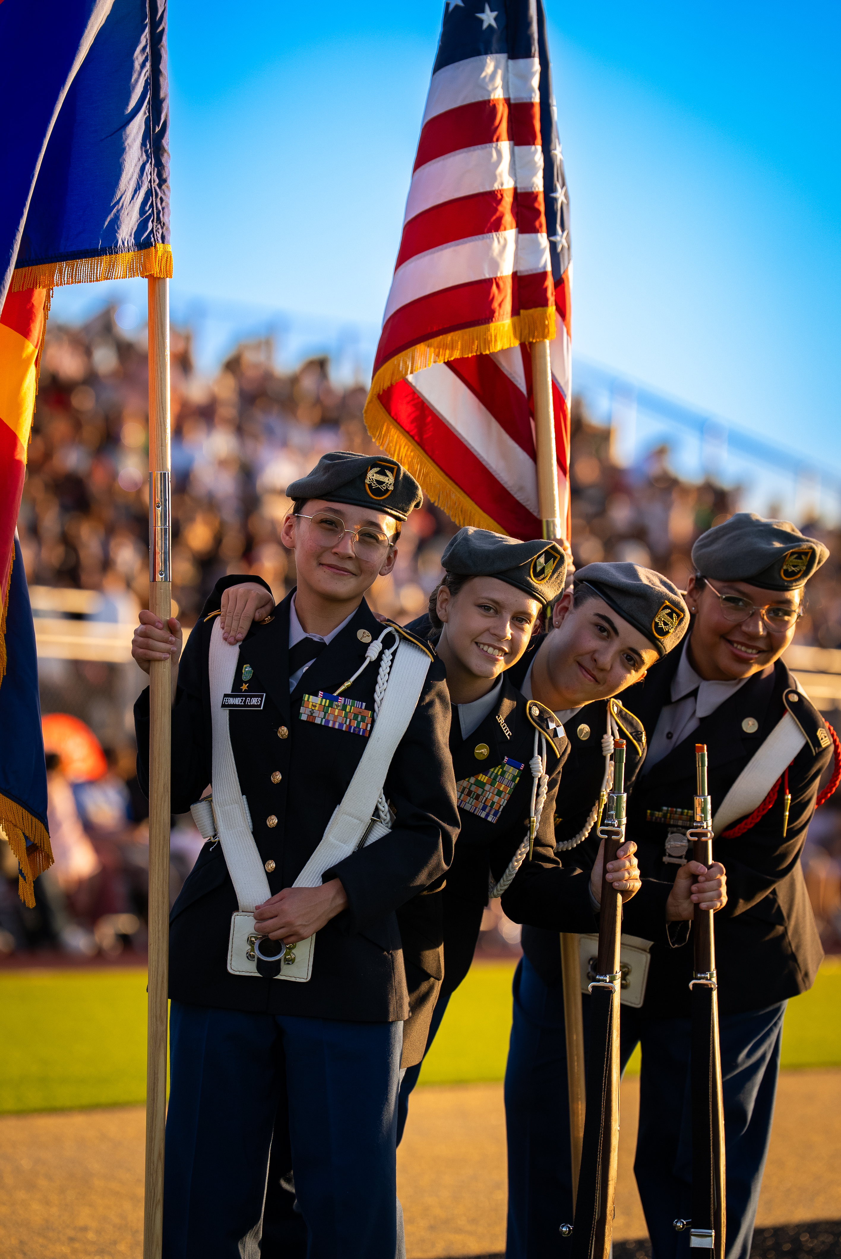 Group of four female students in military uniform holding US flag.
