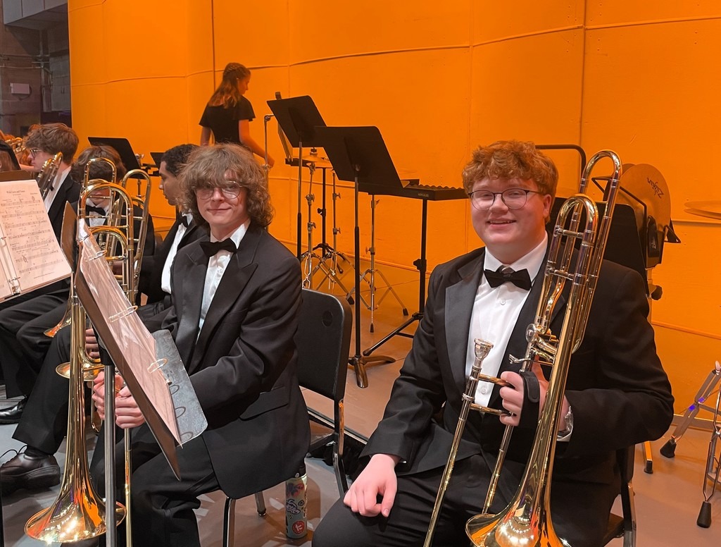 Two band members in tuxedos holding instruments on stage
