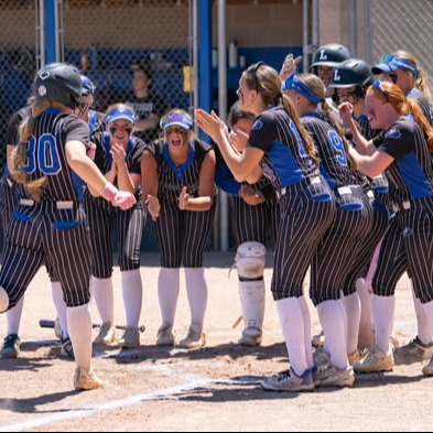 team photo of girls softball team celebrating homerun as player touches plate