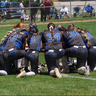 photo of softball team on one knee in a circle on the field