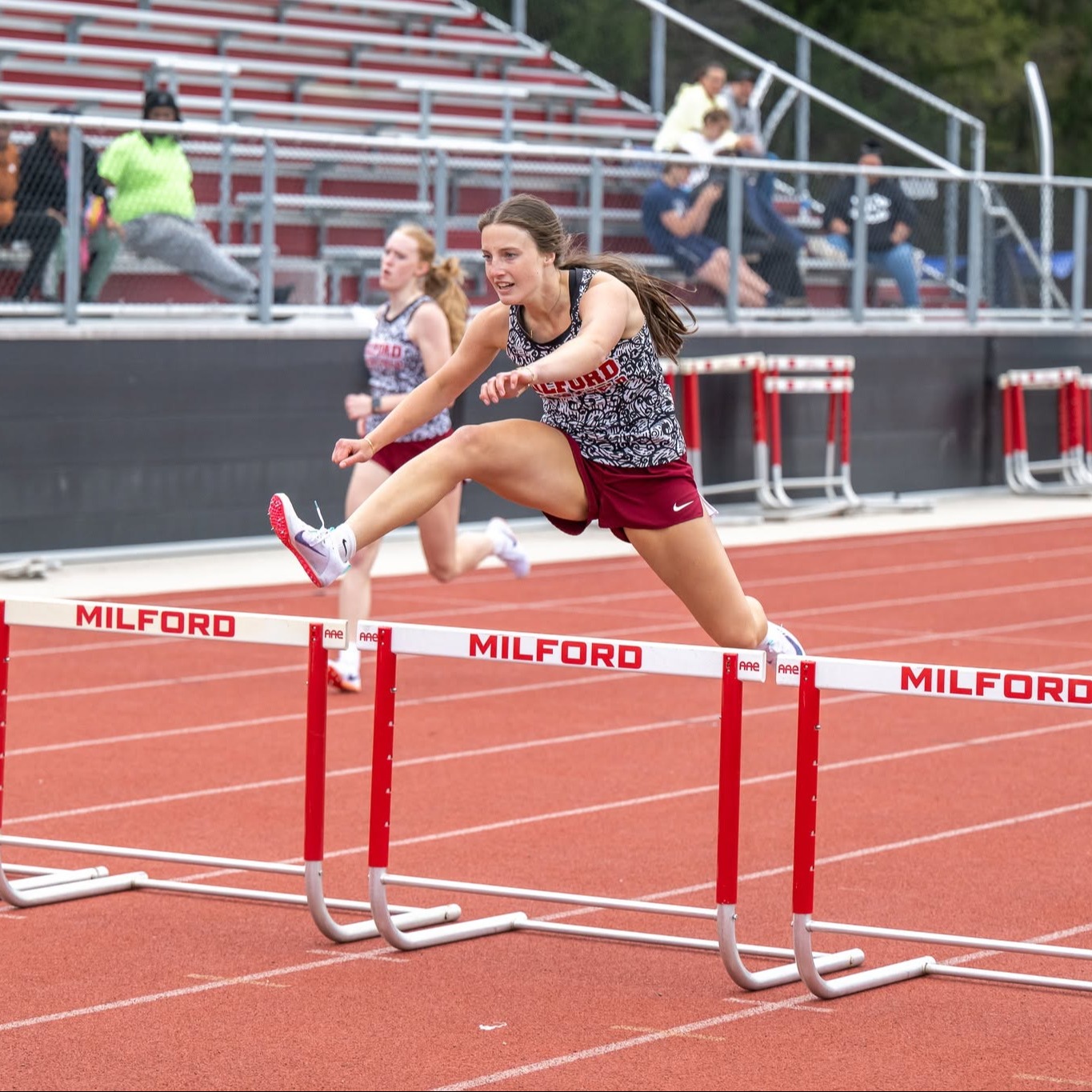 Girl jumping hurdle on track during meet