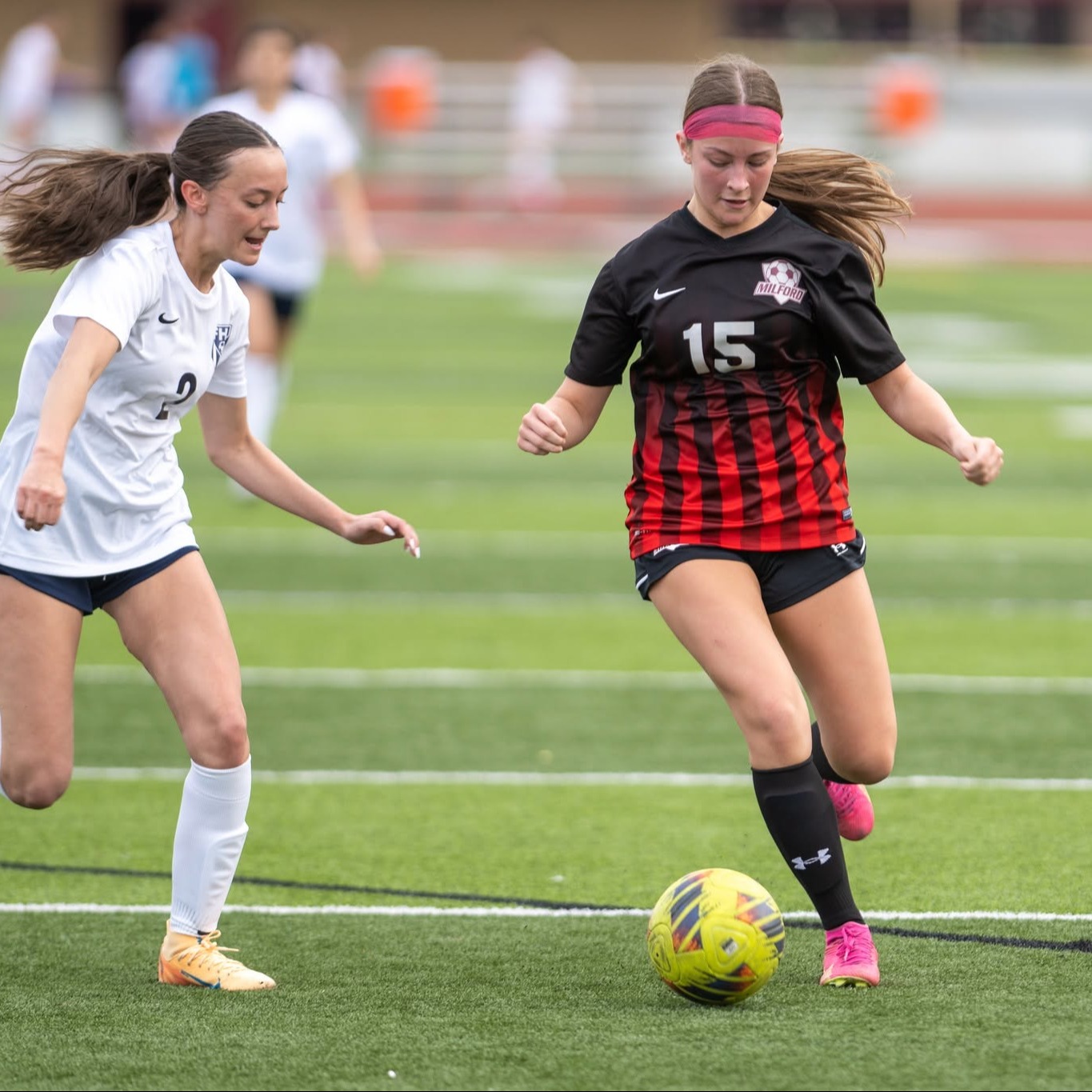 girl soccer player dribbling down the field