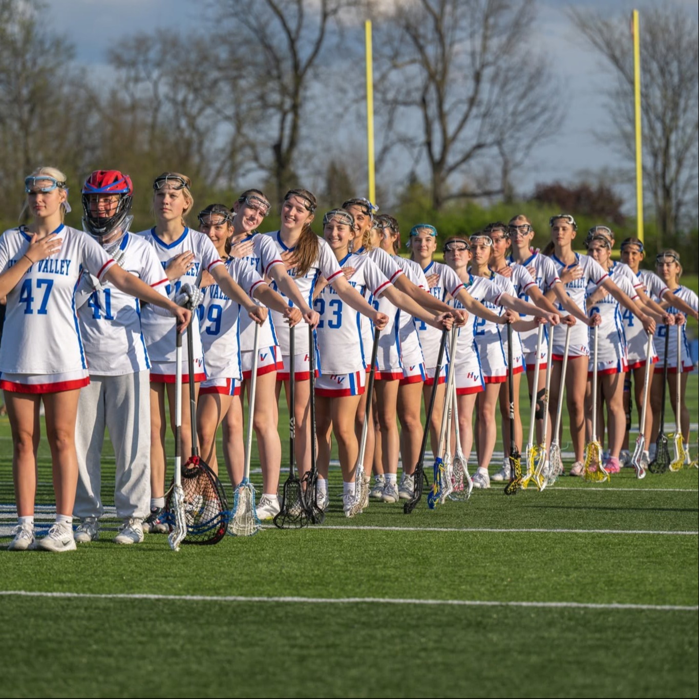 girls lacrosse team stands in a line for anthem