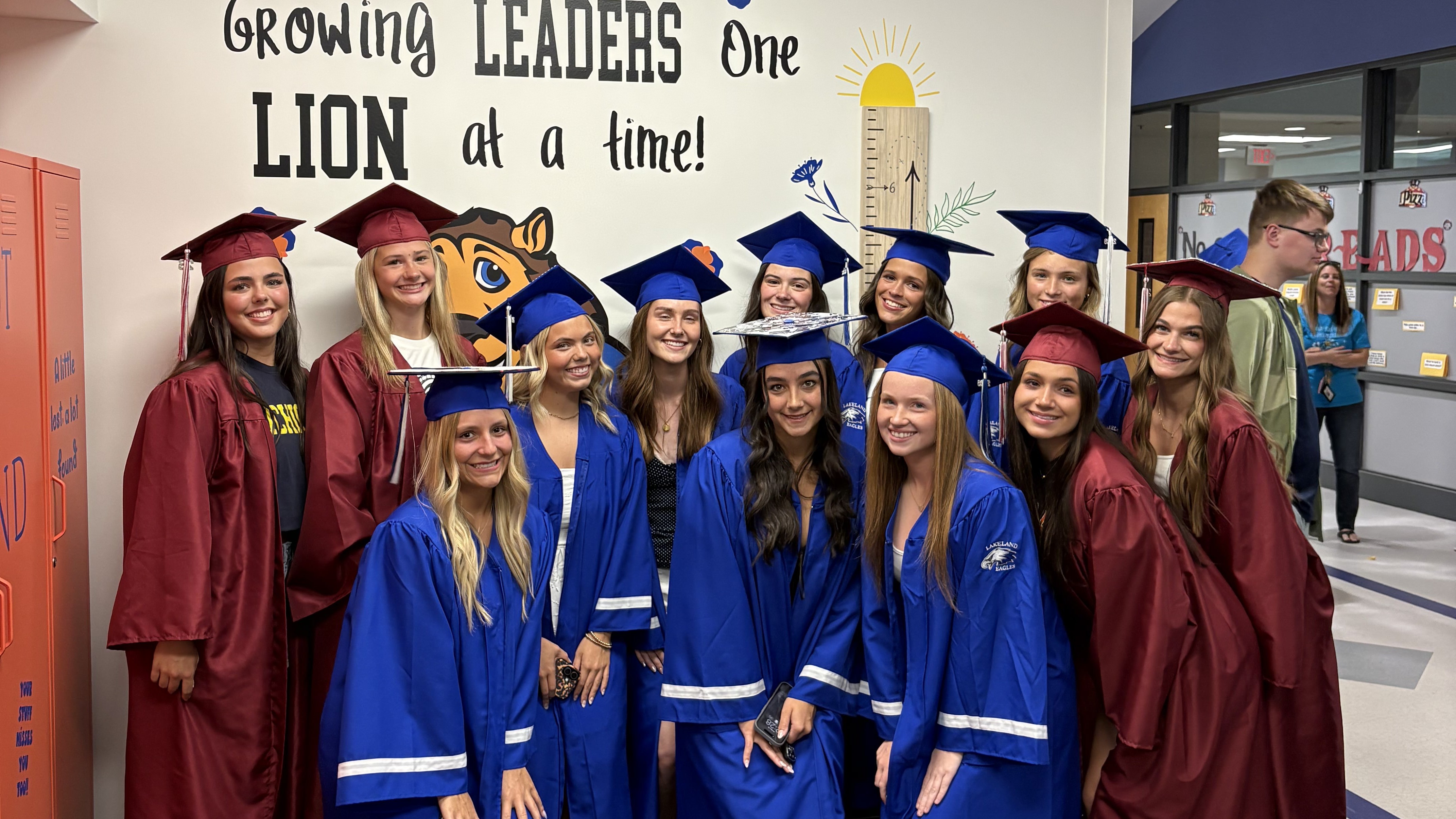 Several students posing for phot in hallway wearing grad caps & gowns