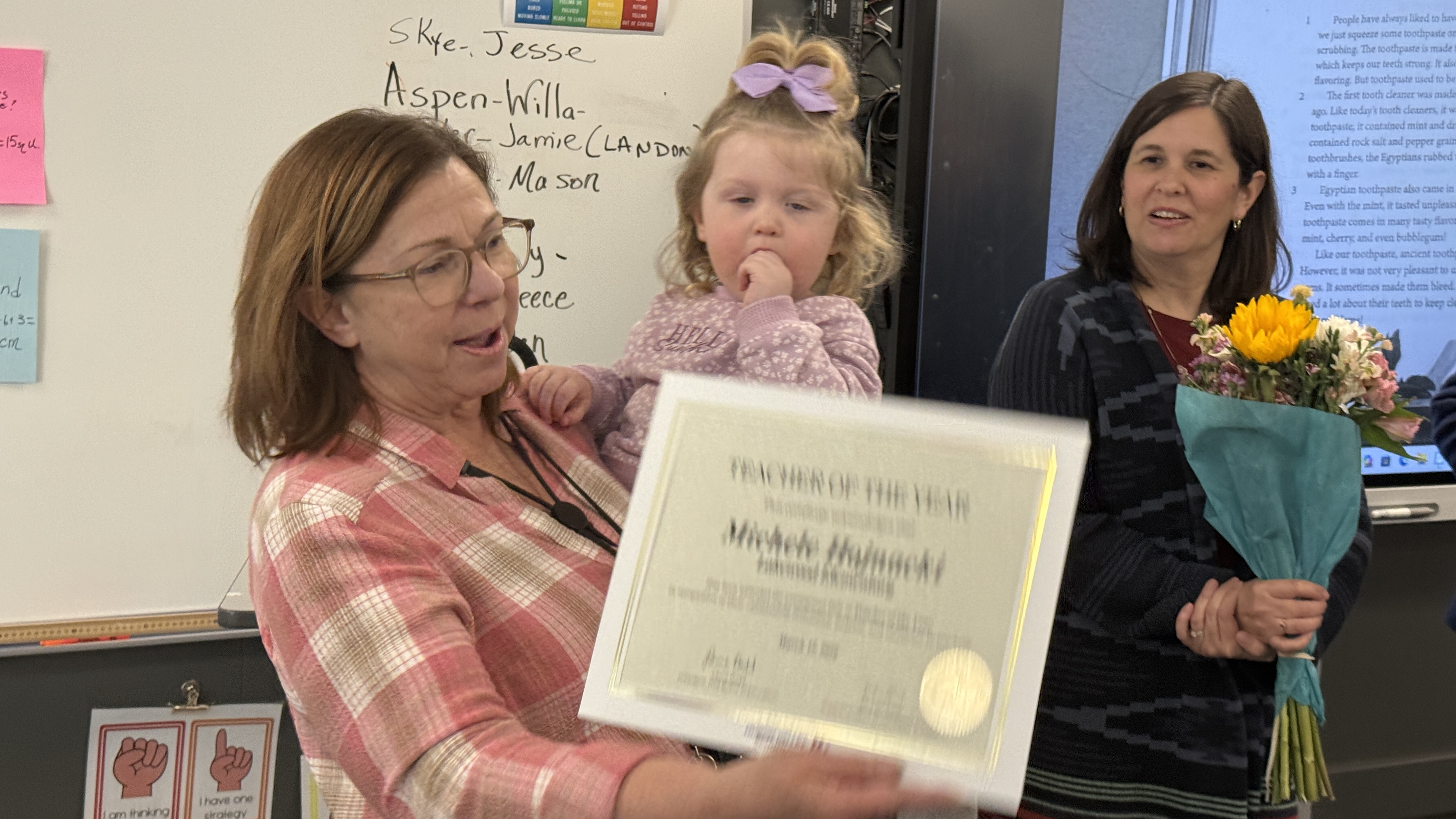 Teacher accepting ward while holding a young child