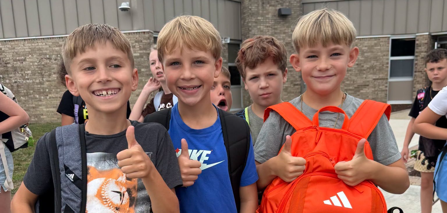 # boys smiling &amp; posing for a picture outside of a school 