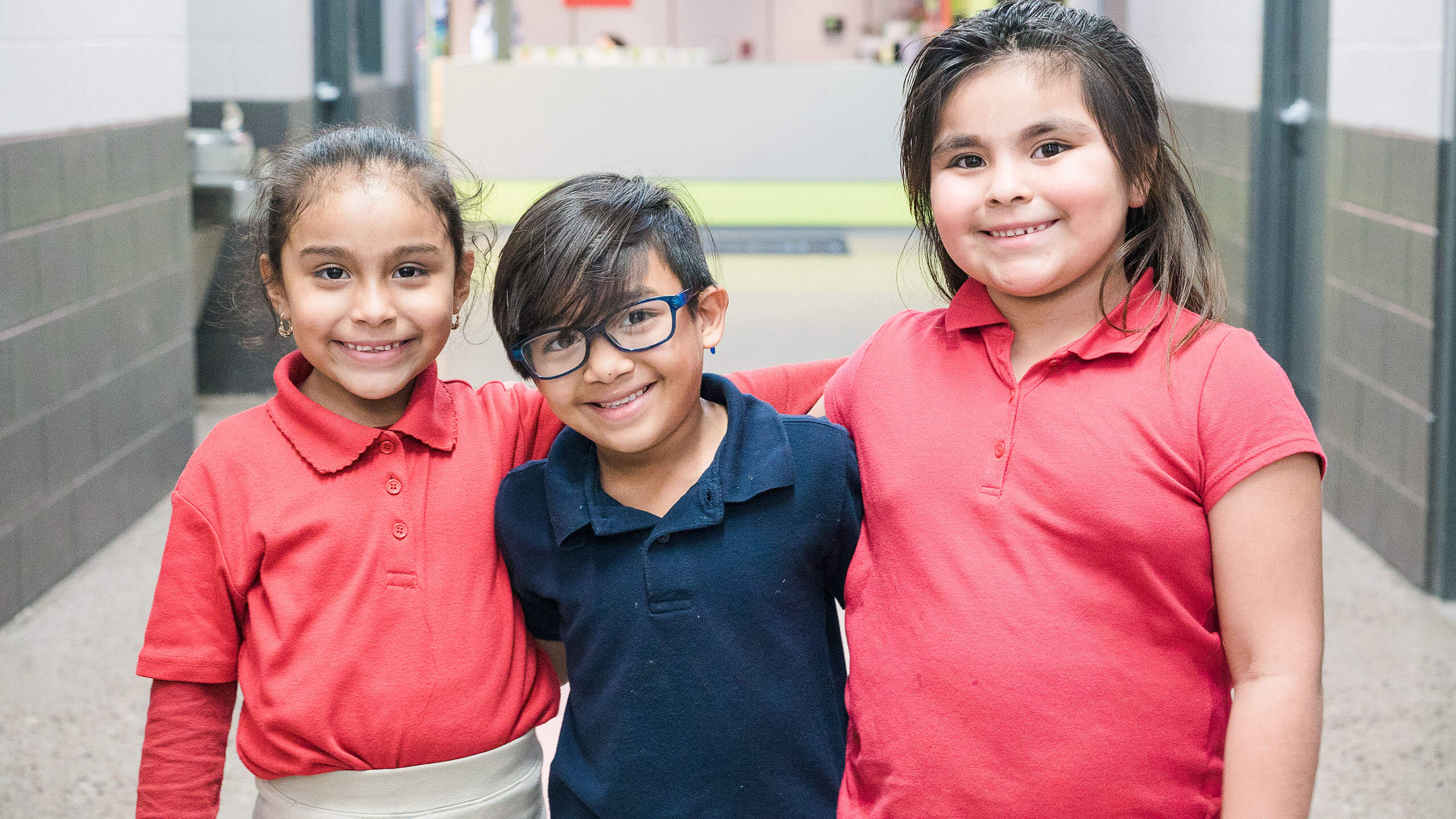 3 students standing with their arms around each other