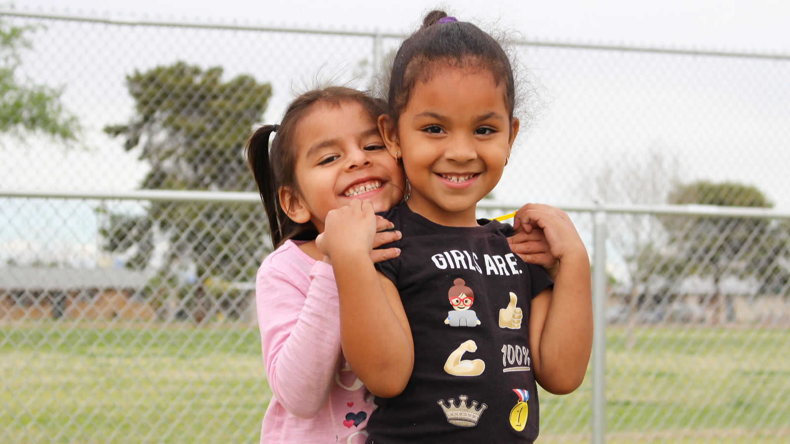 two students standing together one with her hands on the shoulder of the other one