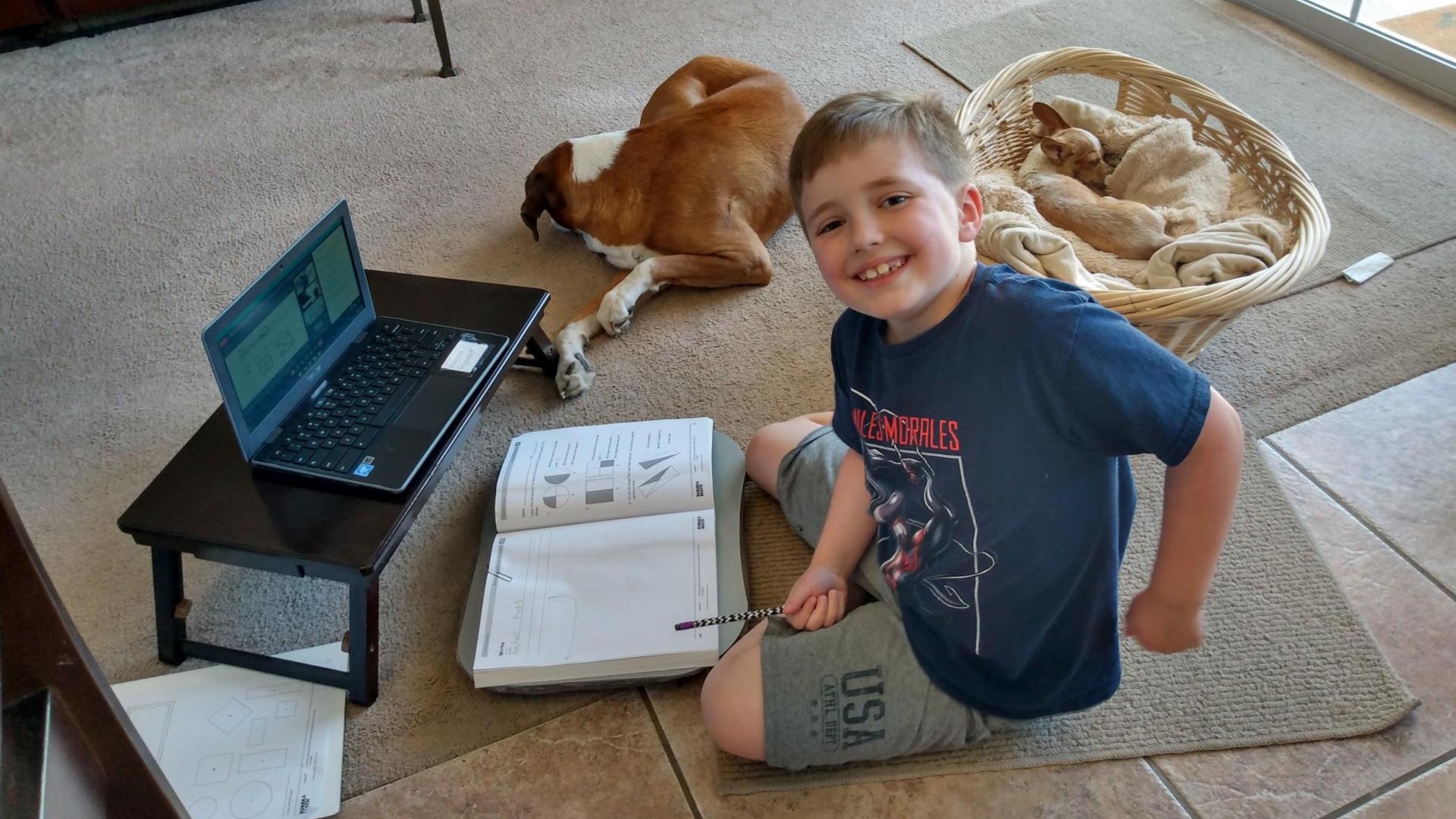 Boy with chromebook and 2 dogs